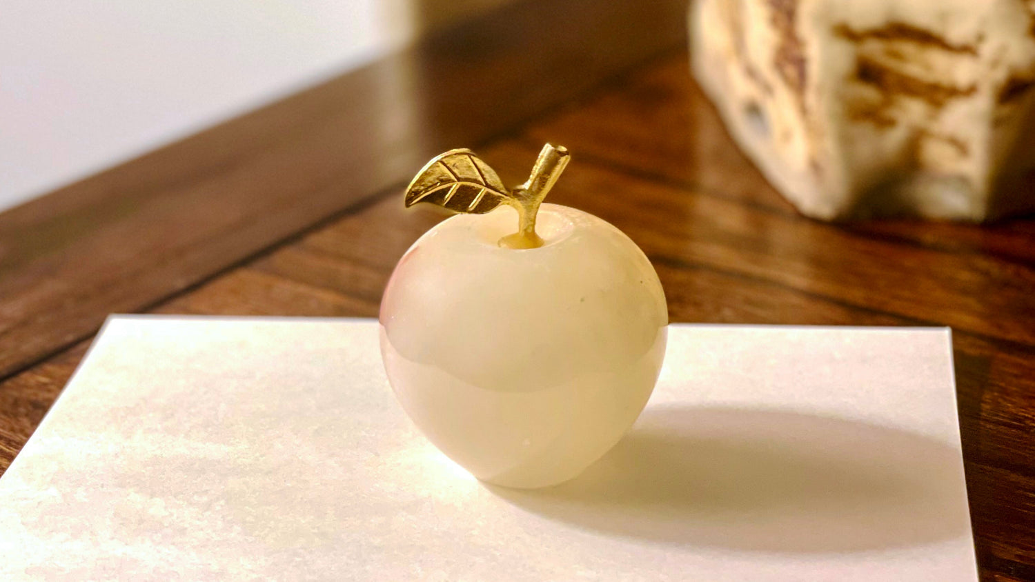 Decorative apple sculpture on a piece of paper with a plant in the background